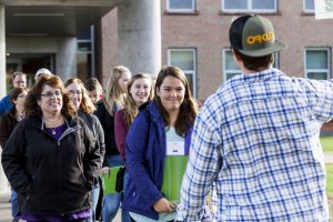 A student tour guide faces away from the camera and speaks to a crowd of about a dozen students and their parents on a tour of Clarkson University. 