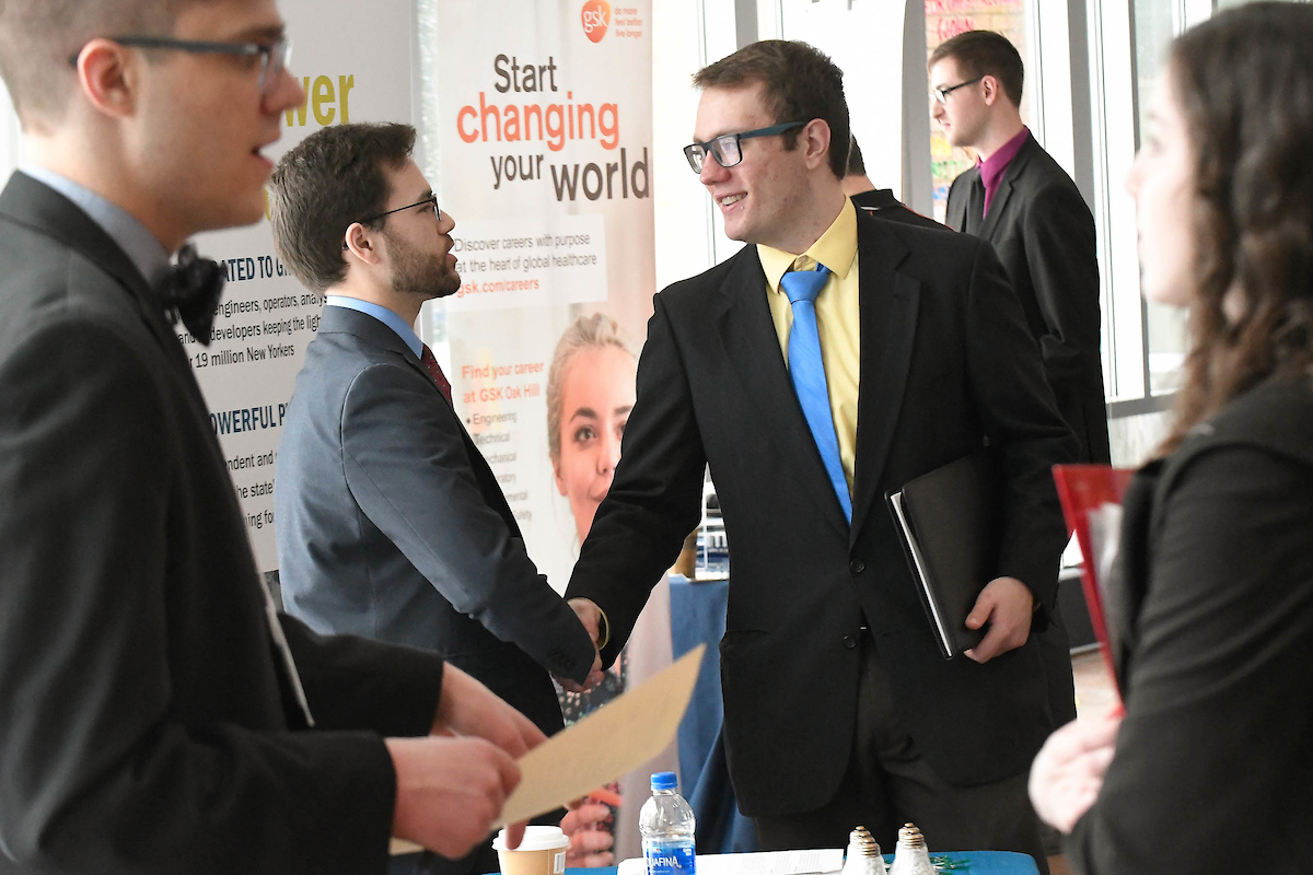 Student shaking hands with an employer in the annual Career Fair on campus