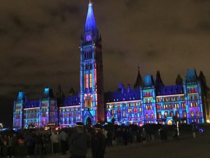 Canada's Parliament illuminated in multiple colors at night. 