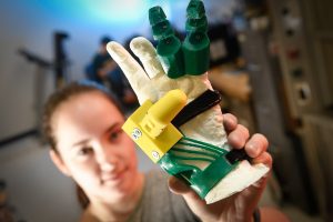 A student holds a 3D printed prosthetic hand.
