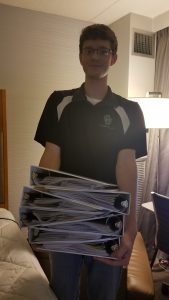 A person holding a heavy stack of binders