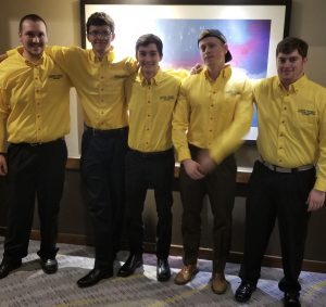 5 people standing together in yellow shirts