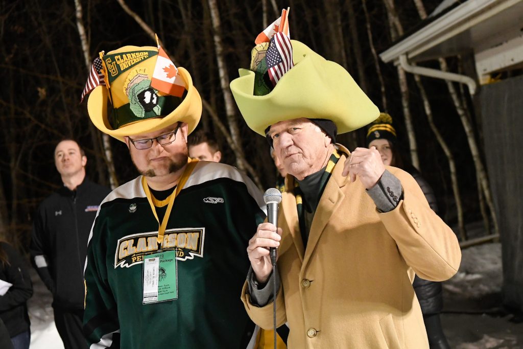 Two men in big yellow cowboy style hats with flags in the brim