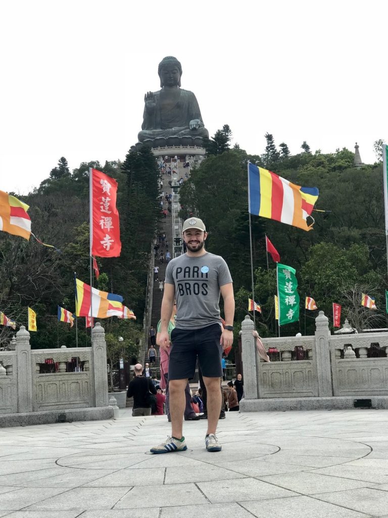 Zachary Golden poses for a photo in front of the Tian Tan Buddha on Lan Tau Island, Hong Kong. 