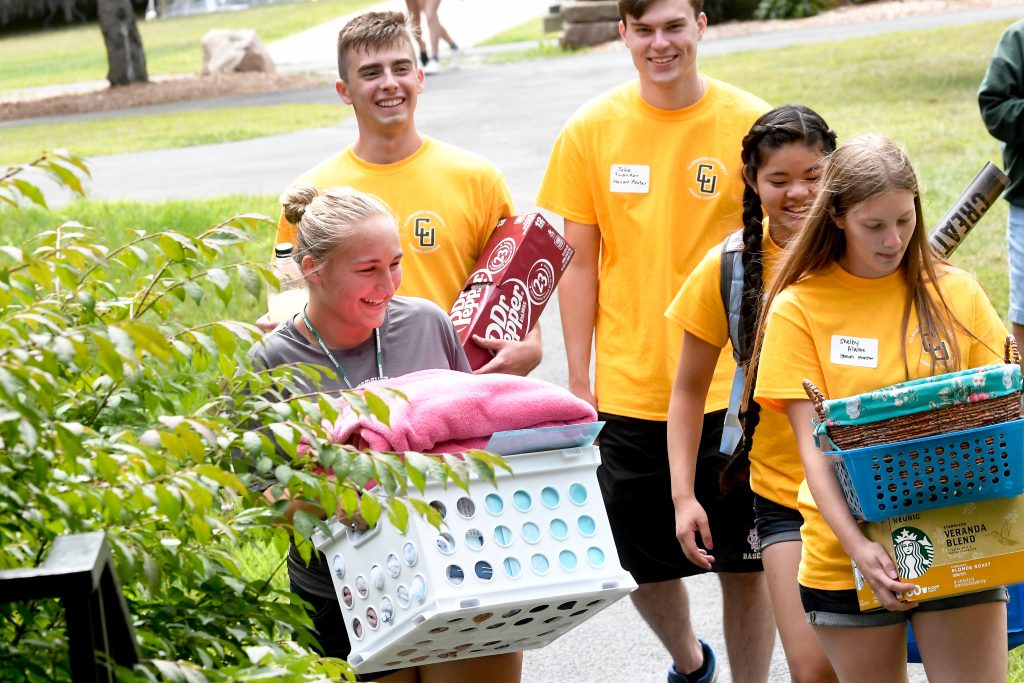 A group of Clarkson Honors students helps a new first year student move in to their residence hall by carrying various items