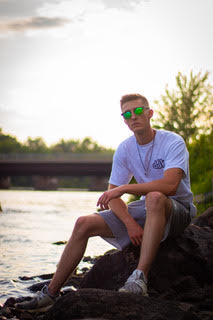 A model has his photo taken while sitting on a large rock overlooking the water by Clarkson student Jada Flanagan in downtown Potsdam, New York. 
