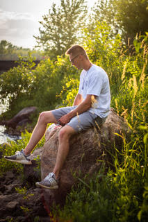 A model has his photo taken while sitting on a large rock by Clarkson student Jada Flanagan in downtown Potsdam, New York. 