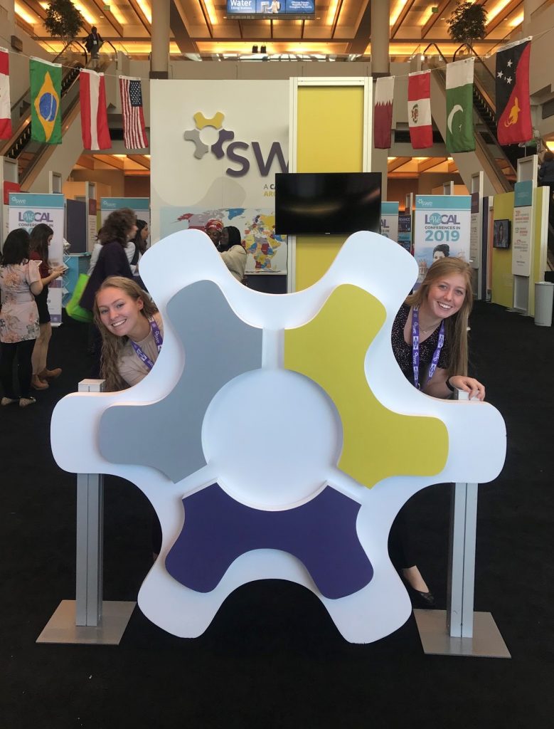 Callie Lindsay and Kate McKinley standing behind a logo display at the National SWE Conference