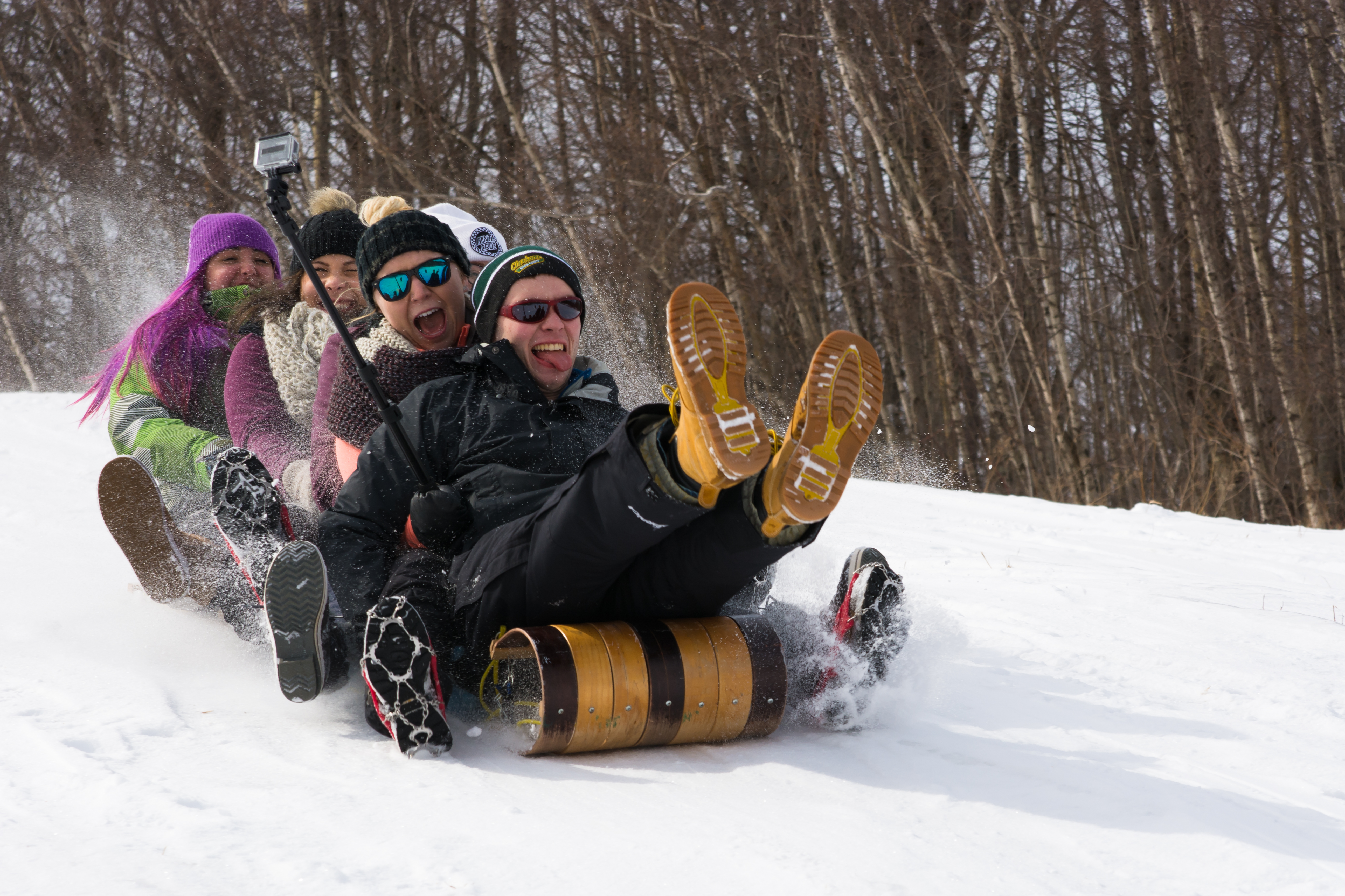 A group of student sledding down the hill on a wooden sled