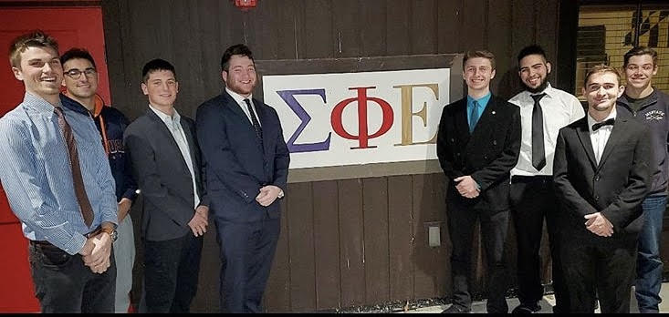 Sigma Phi Epsilon fraternity brothers standing in front of their house