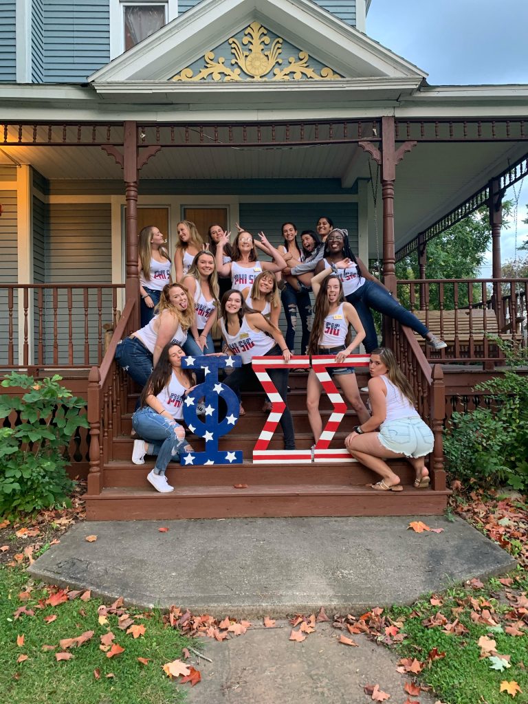 Phi Sigma Sigma sorority sisters posing on their front steps by their house