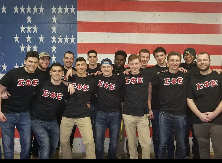 Sigma Phi Epsilon brothers in front of a painted flag on a wall