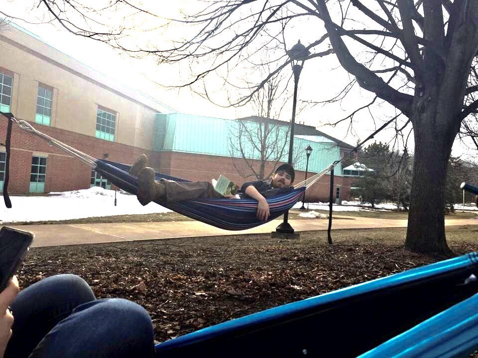 Toby sitting in a hammock outside of the CAMP academic building.