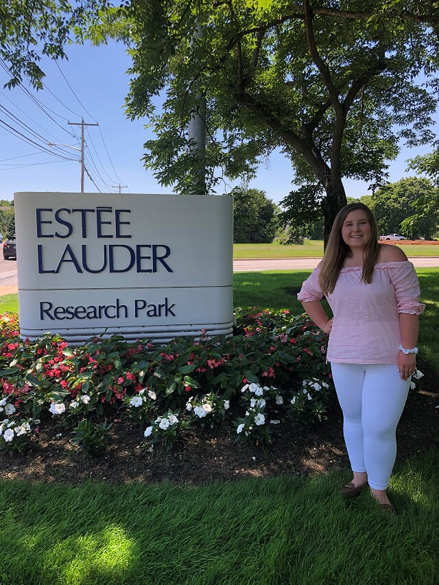 Megan standing next to an 'Estee Lauder' sign during her internship