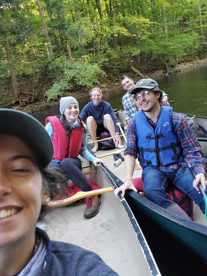 Students smiling at the camera on canoes.