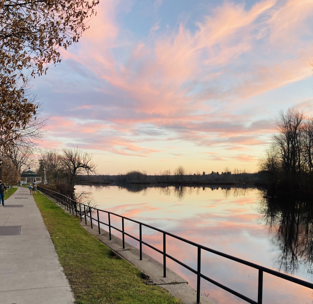 The path along the Racquette river into Ives park with a blue and pink sunset