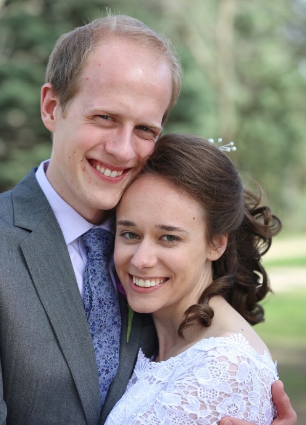 A couple smiling into the camera on wedding day