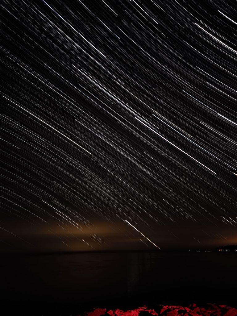 star trails made from a long exposure over a black foreground 