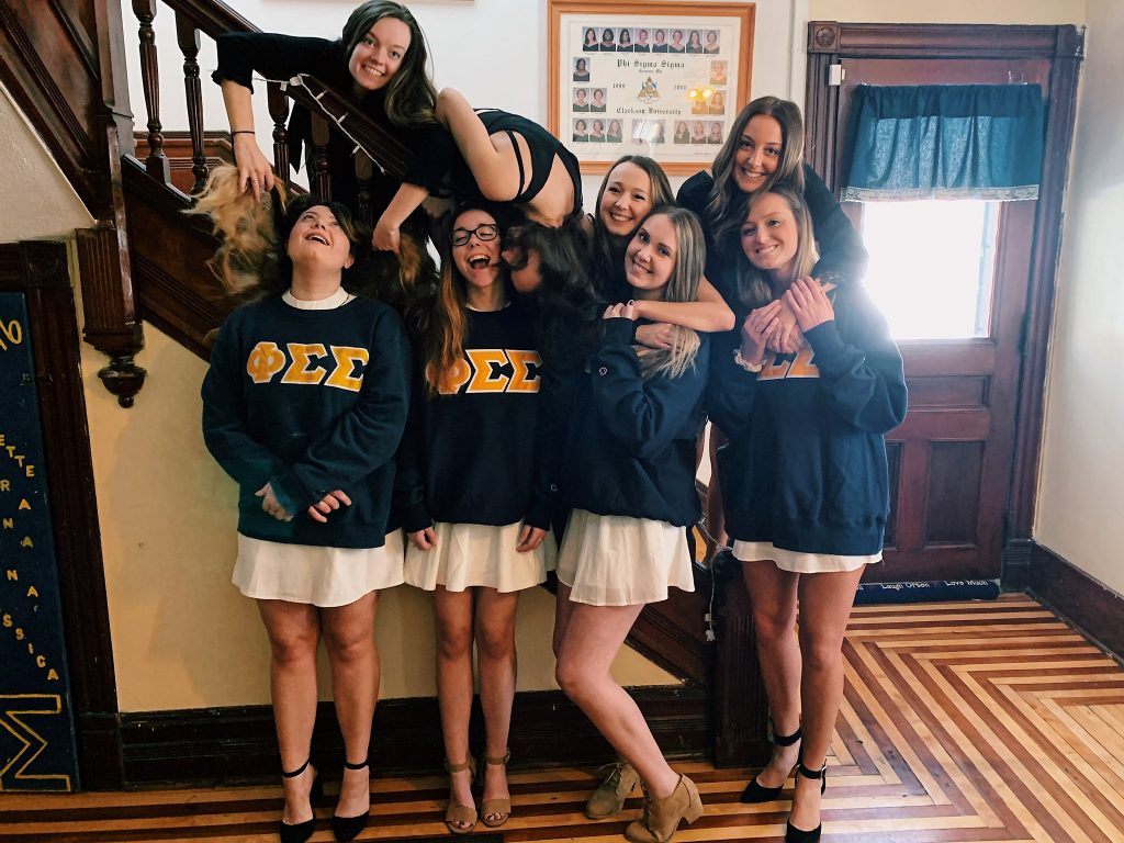 Megan Walseman standing on the stairs of a sorority house with her sorority sisters