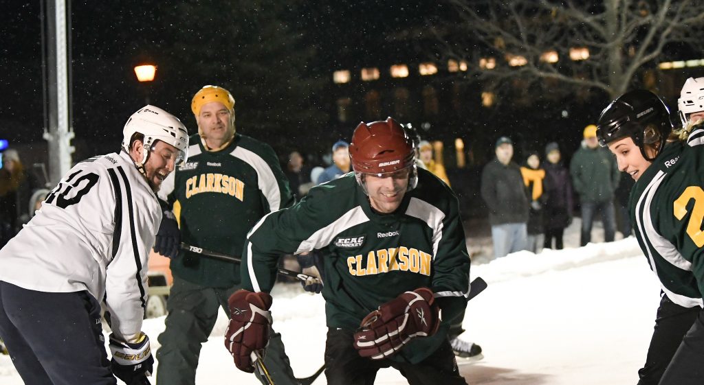 Alumni playing hockey on the outdoor rink during COGO, or Cold Out Gold Out
