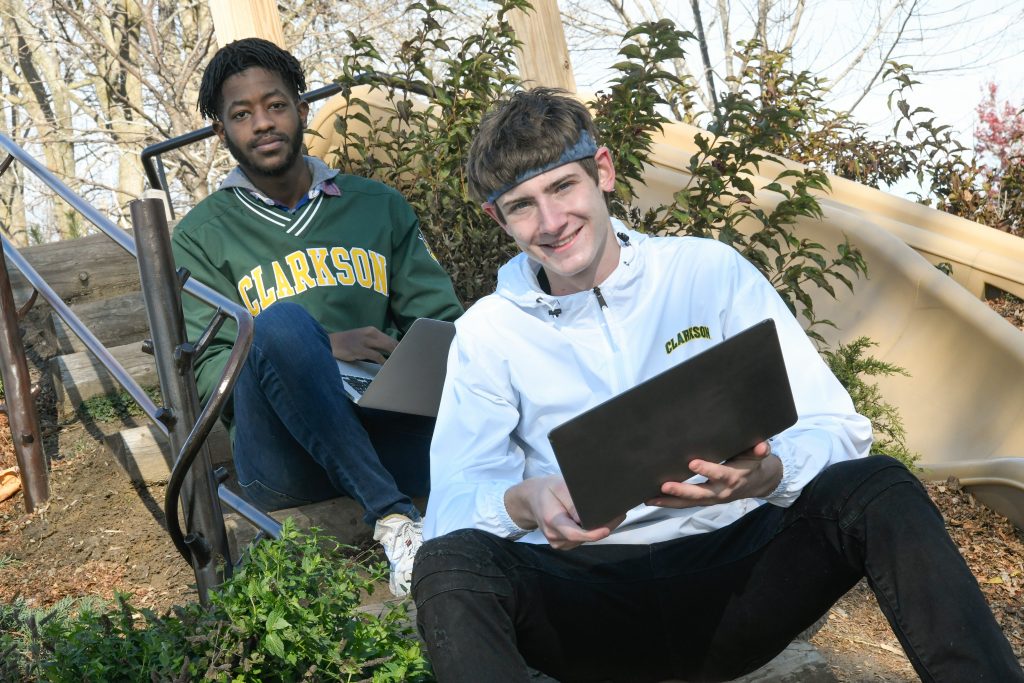 Clarkson student Max Powers poses with a laptop and his business partner Selorm Bruce, also a Clarkson student.