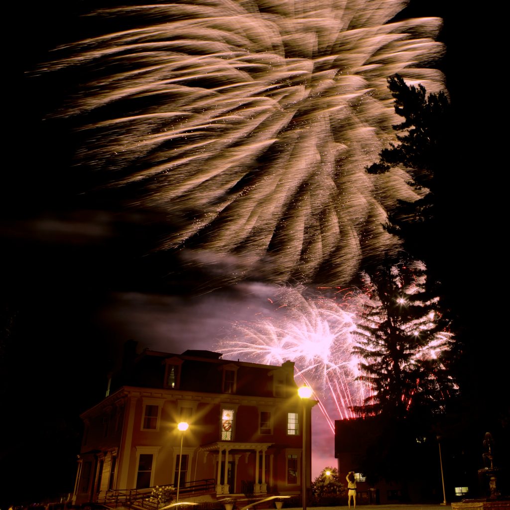 Fireworks blooming in the night sky over Holcroft House, Clarkson University