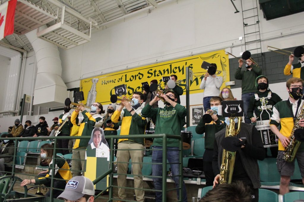 Members of the Clarkson Pep Band play instruments at Cheel Arena at Clarkson University during a hockey game.