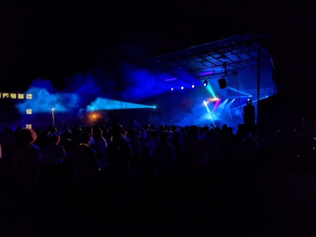 Blue lights illuminate the crowd of people facing a stage