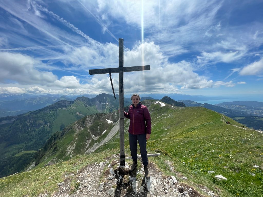 A person standing on top of a mountain next to a cross