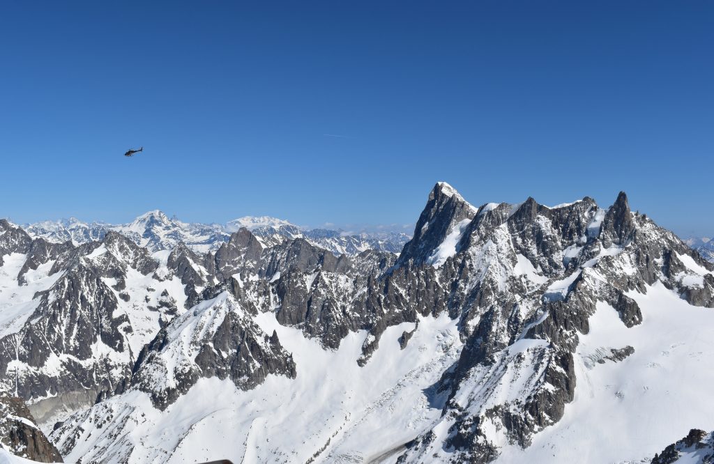 A helicopter flying over a snow covered mountain range 