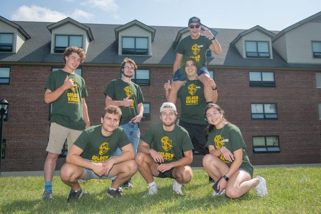 7 students smiling while waiting to move new students into dorms