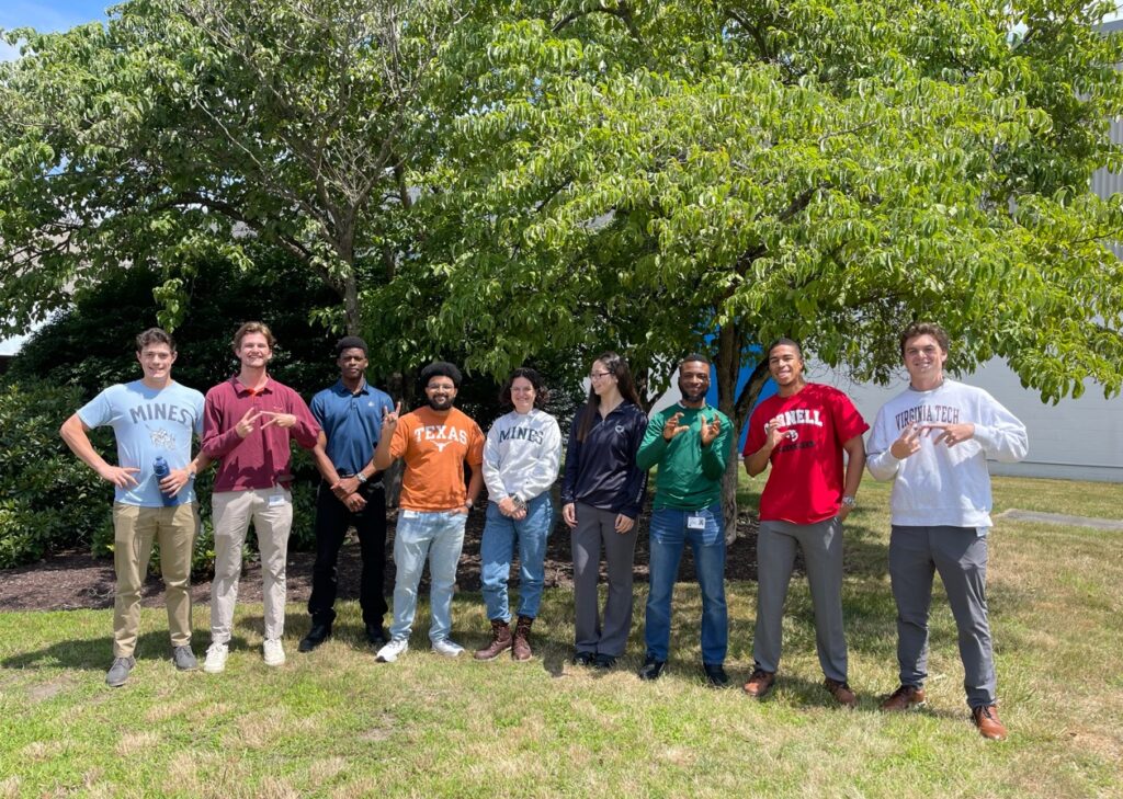 A group of student interns working at Corning Incorporated show their school pride by wearing their universities' apparel 