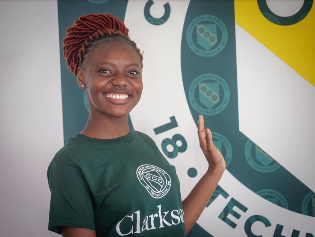 Clarkson University international student Chidiogor Ofodum smiles in front of the school logo