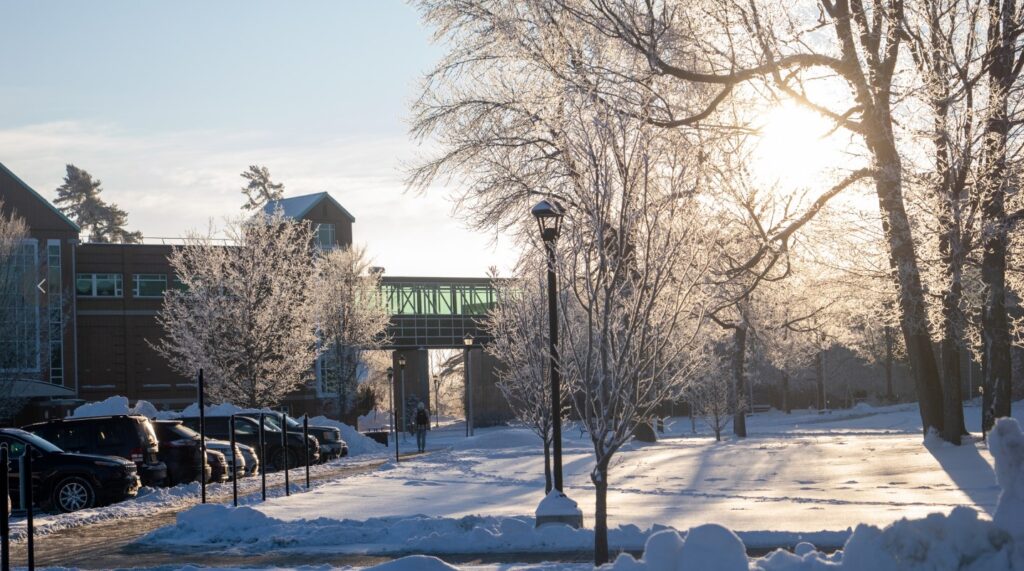 Winter landscape of Clarkson University featuring snowy trees, Snell Hall and the walkway bridge to the Science Center 