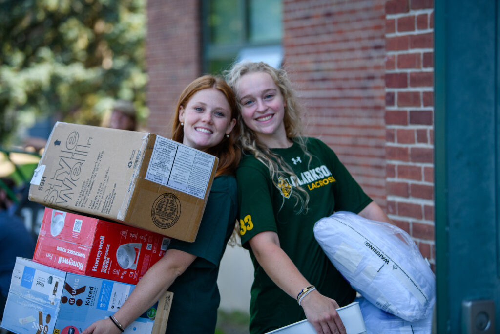 Two female Clarkson University students help move-in freshman students to unpack for college
