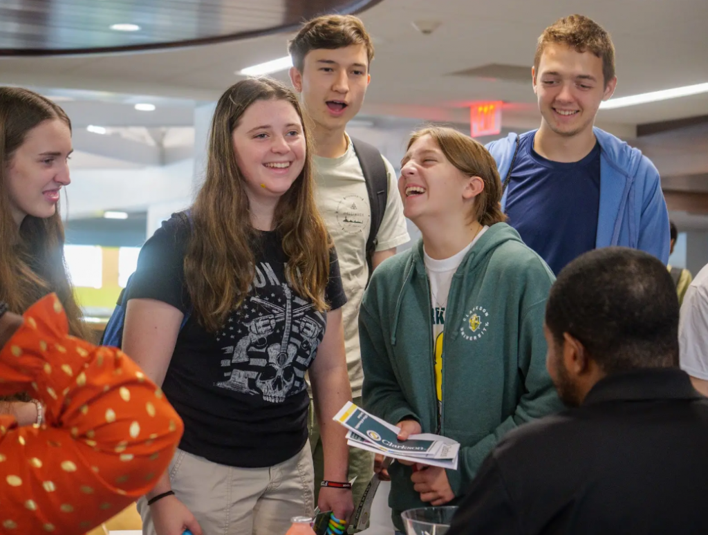 A group of students stand together and laugh.