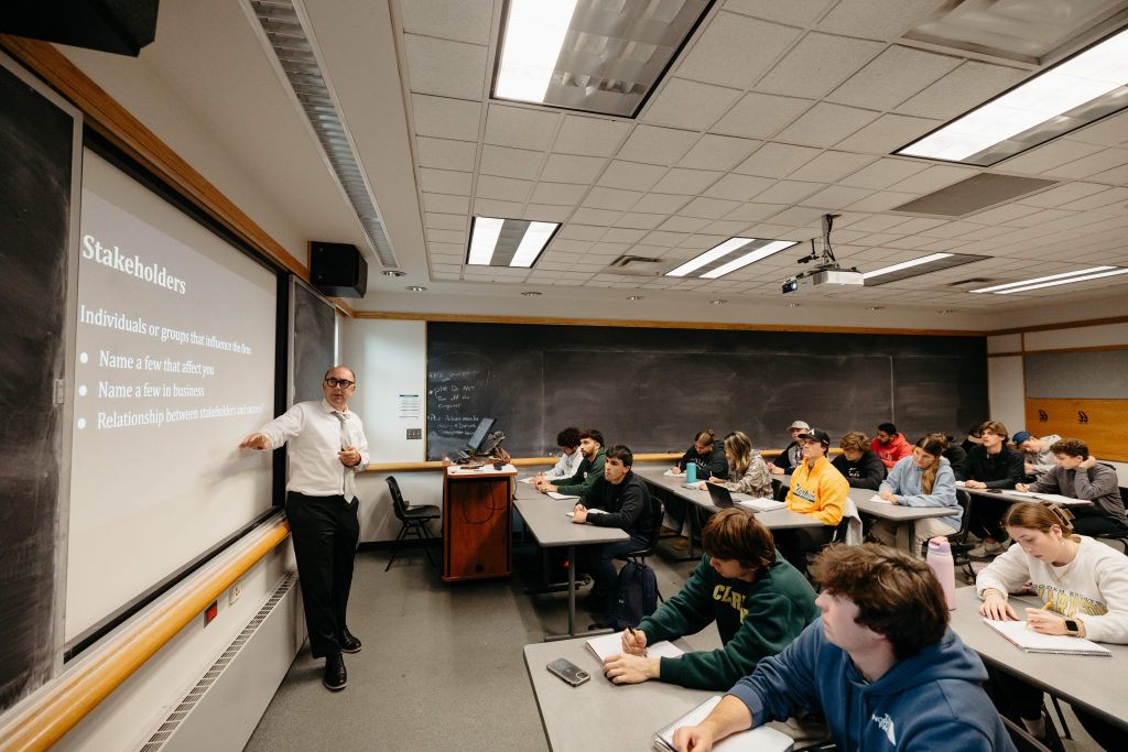 Professor teaching a Business Administration class at Clarkson University to engaged students in a traditional classroom setting.