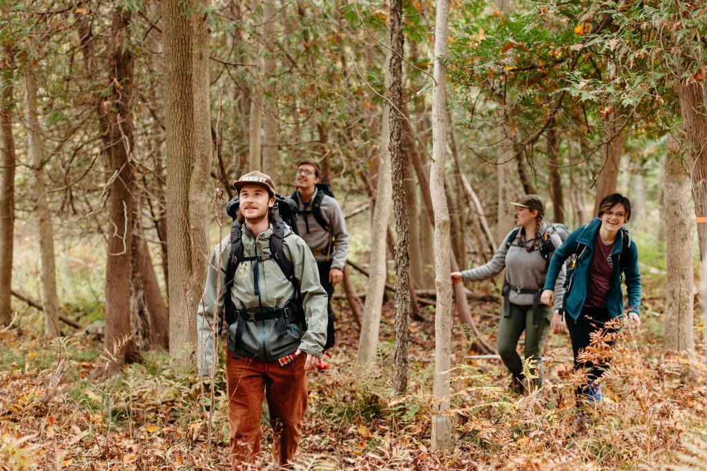Group of students hiking through a forest in fall.