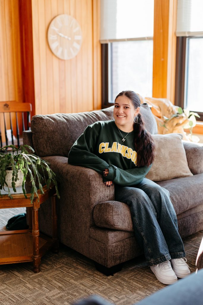 A female Clarkson University student sits on a couch