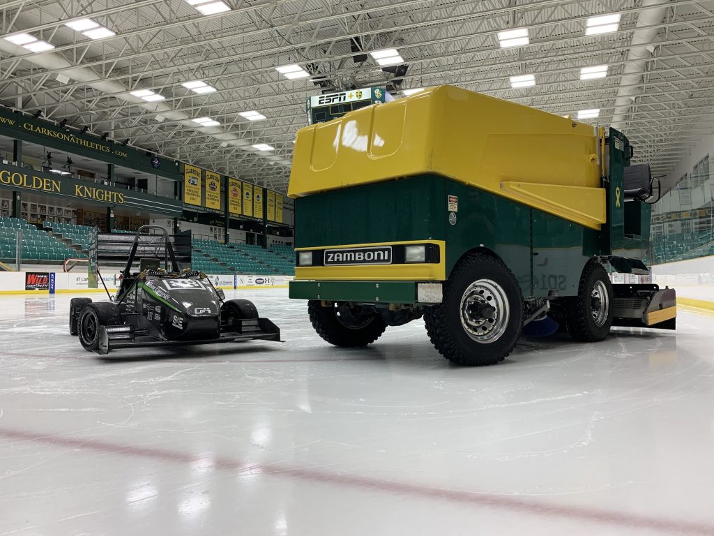 Clarkson University’s Formula SAE race car parked on the ice next to a Zamboni inside Cheel Arena.
