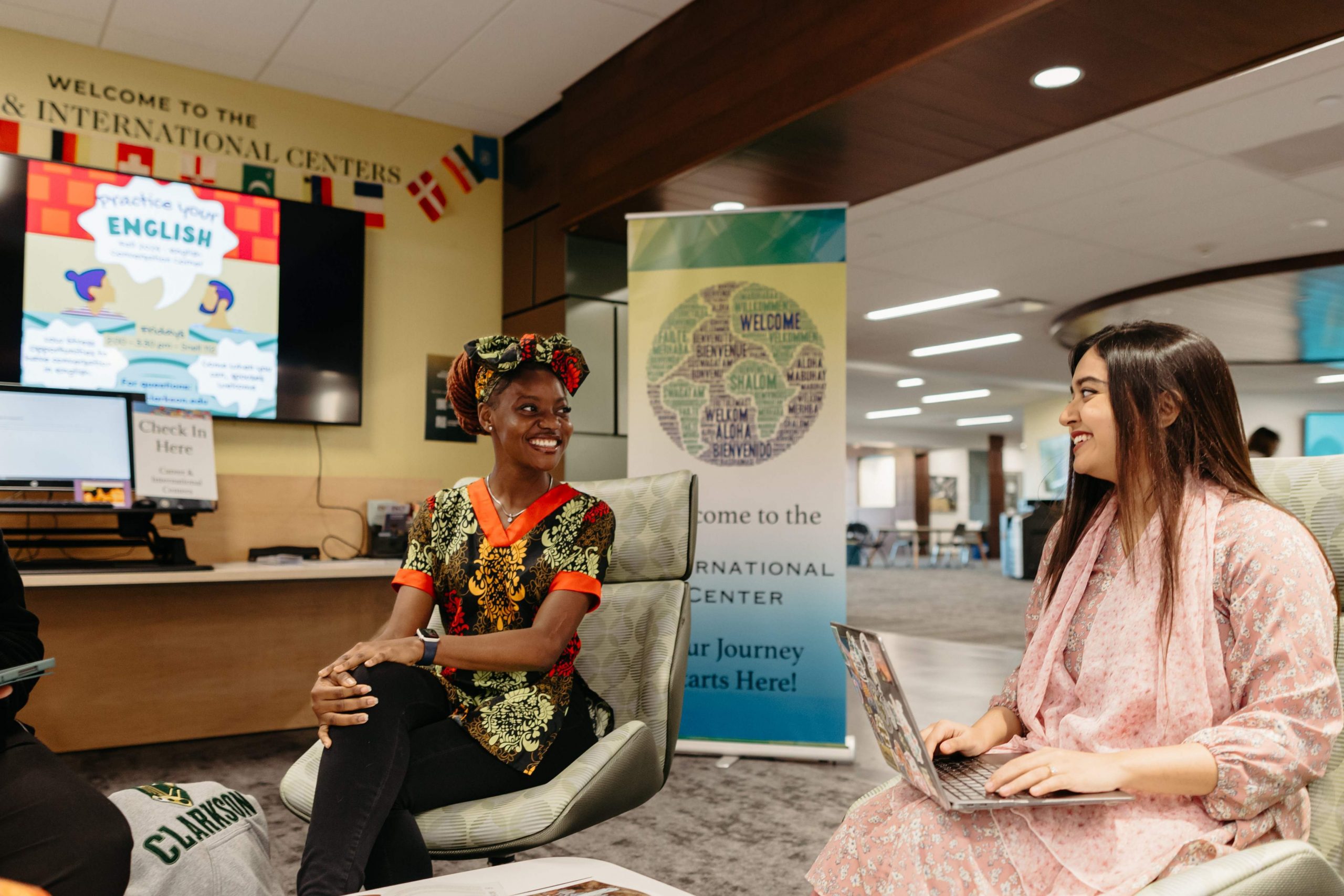 Two students in traditional attire talk and smile at Clarkson’s International Center during a cultural gathering.