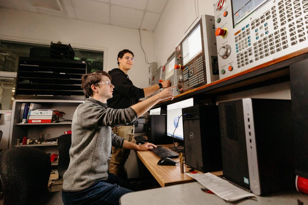Two Clarkson students work together to program CNC machines in the SPEED machine shop.