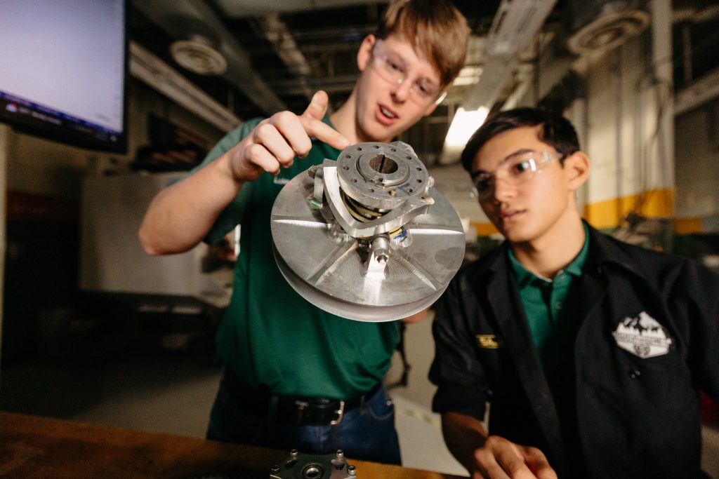 Two Clarkson students examine a machined assembly in the SPEED program machine shop.