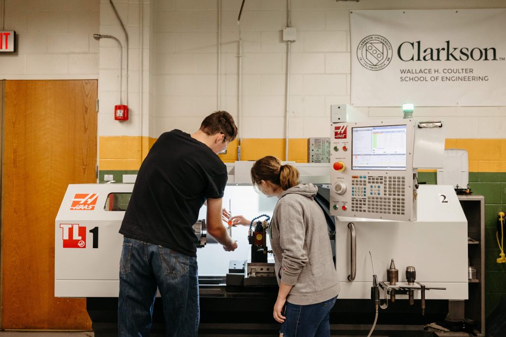 Two Clarkson students operate a HAAS TL-1 lathe in the university’s prototyping shop.