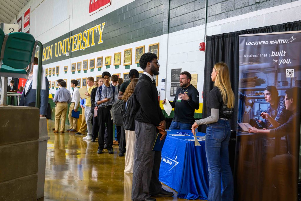 Students speaking with recruiters at the Lockheed Martin table inside Clarkson University’s Alumni Gym during the Fall 2025 Career Fair. A banner reads “A career that’s built for you.”