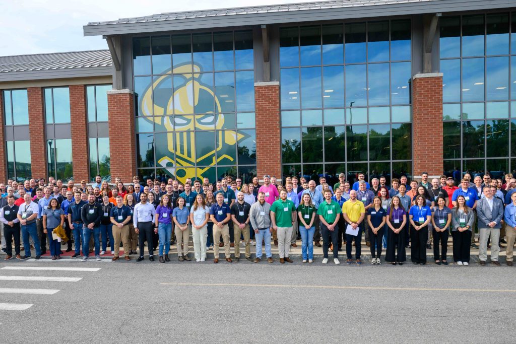 Large group of alumni employers gathered outside Clarkson University’s Student Center during the 2025 Fall Career Fair, standing in front of windows displaying the Golden Knight logo.
