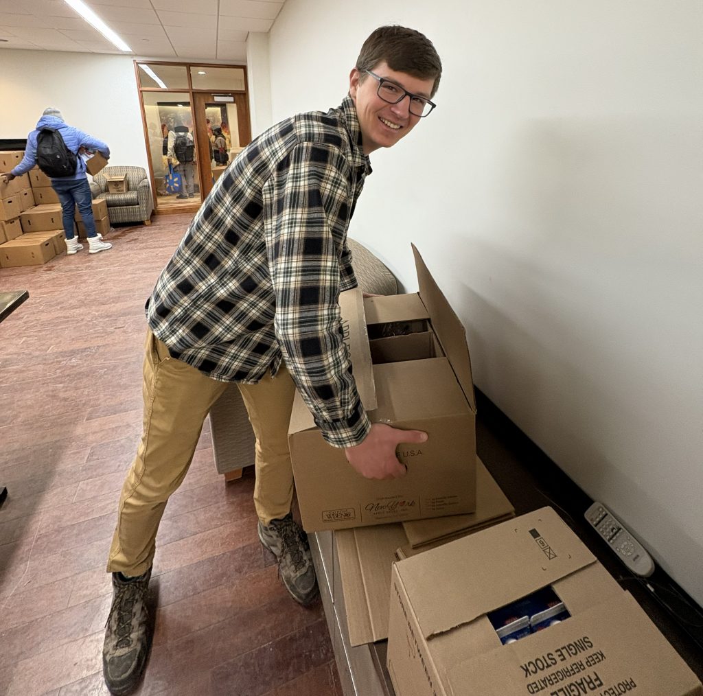 A student stacks boxes of food in the CU Pantry.