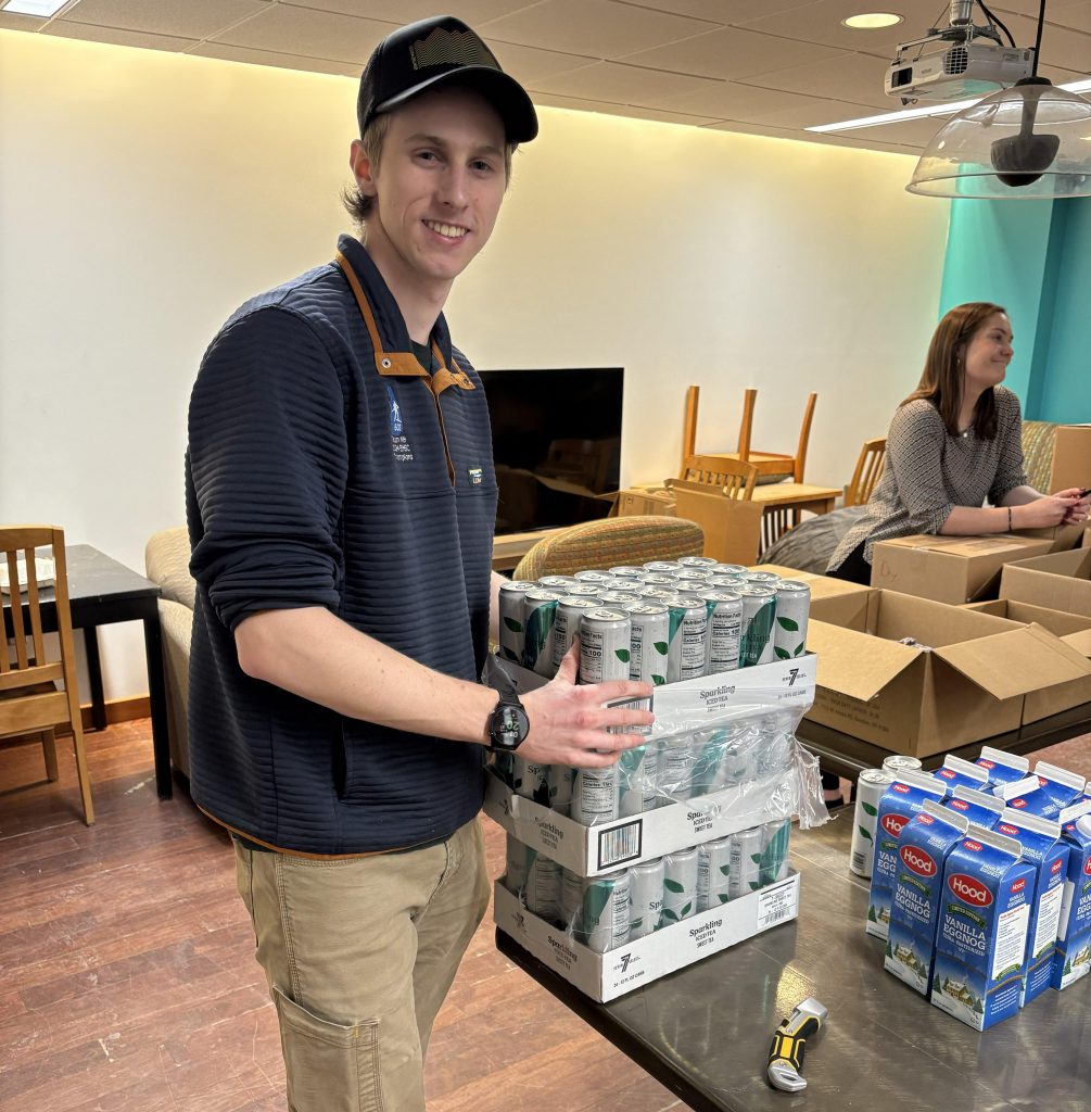 A student stacks boxes of food in the CU Pantry.