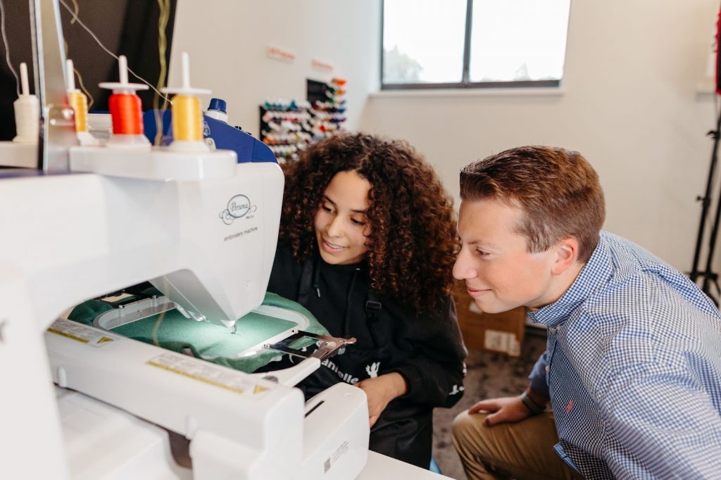 Two students examine a sewing machine in the Makers’ Loft.
