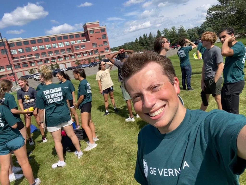A group of students, wearing GE Vernova-branded attire, stand around on a field.

